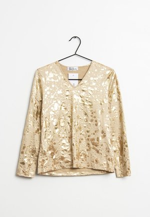 Camicia a maniche lunghe metallica dorata con scollatura a V, caratterizzata da un motivo splash e una texture liscia e lucida. Esibita su un appendiabiti.