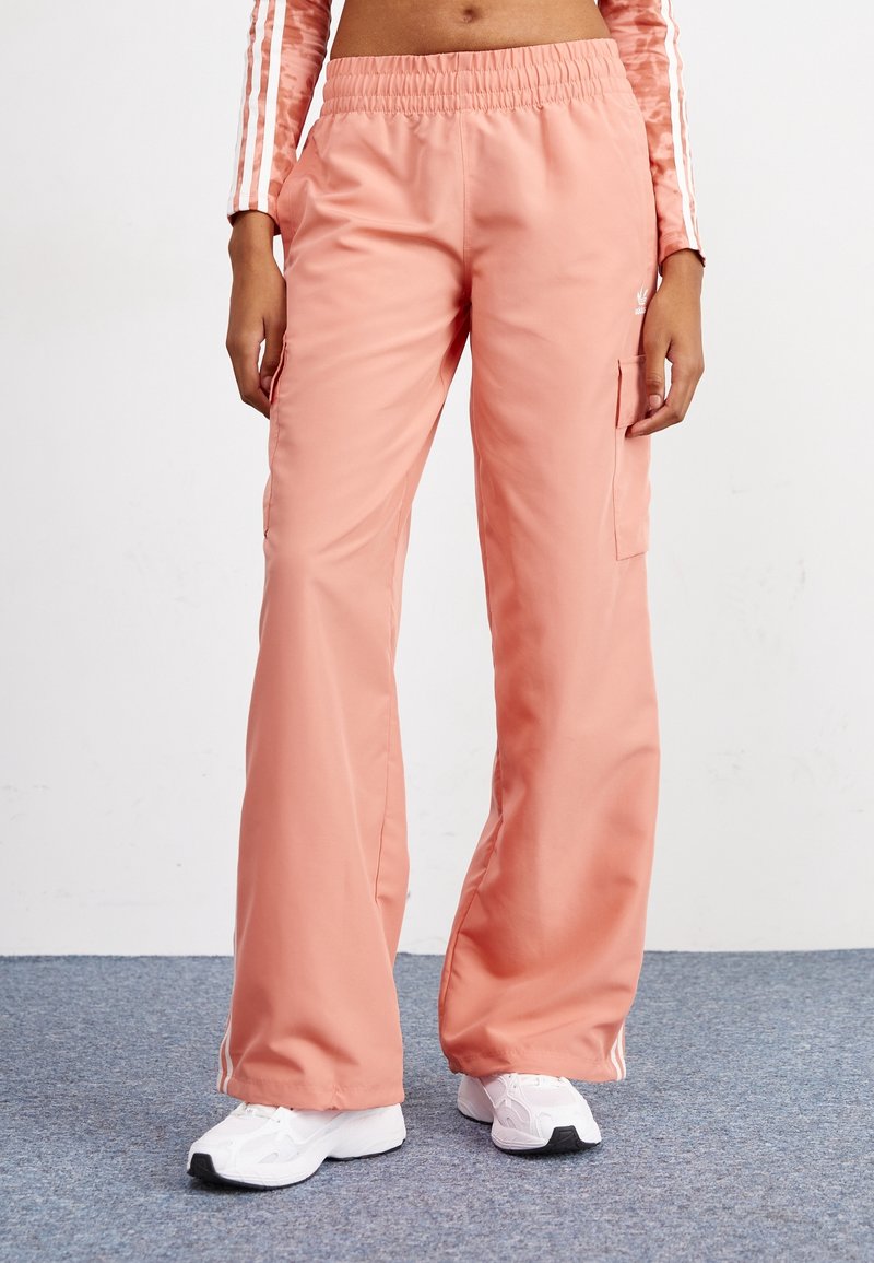 Vaaleanpunaiset cargo-housut, joissa on joustava vyötärö, leveät lahkeet ja sivutaskut. Materiaali näyttää sileältä ja kevyeltä, sopii arkipukeutumiseen.