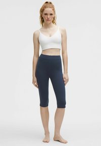White crop top and navy capri leggings made of smooth, stretchy fabric. The top has thin straps and a rounded neckline.