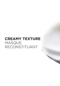 Masque blanc crémeux à la texture lisse ; comporte le texte « Texture Crémeuse » et « Masque Reconstituant » en police noire en gras.