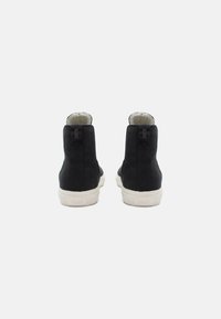 Zapatillas altas negras de ante, con un forro interior de felpa, una resistente suela de goma blanca y un sutil logo en la parte trasera.