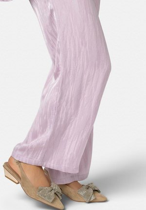 Beige Veloursleder Slingback-Schuhe mit niedrigen Blockabsätzen und großen Strassschleifen, kombiniert mit hellvioletten Hosen mit weitem Bein.