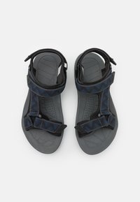 Sorte og blå sandaler med justerbare stropper, teksturert grå fotbed og mønsterdesign på de øvre stroppene. Gummisåle med riller.