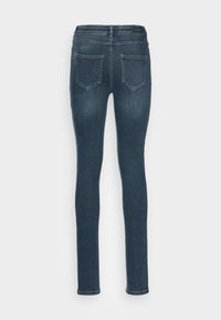 Jeans ajustados de denim azul oscuro, con una cinturilla de altura media, diseño de cinco bolsillos y un sutil efecto de desgaste en la superficie del tejido.
