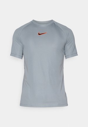 T-shirt de sport gris en tissu lisse et léger, avec des manches courtes et un logo Nike orange bien visible sur la poitrine.