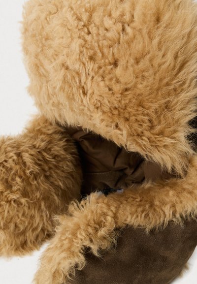 Botine din materiale sintetice, căptușite cu blană moale, de culoare maro, având un exterior texturat și un guler pufoșel, de culoare bej, cu un interior neted, de culoare maro.