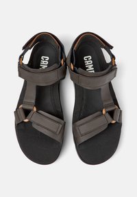 Sandalias negras con múltiples correas ajustables, con acentos marrones redondos y una plantilla texturizada para mayor comodidad. Diseño elegante y minimalista.