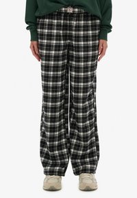 Czarno-białe spodnie w kratę o szerokich nogawkach, wykonane z miękkiej tkaniny, z luźnym krojem i elastycznym pasem. Ozdobione metką z tyłu.