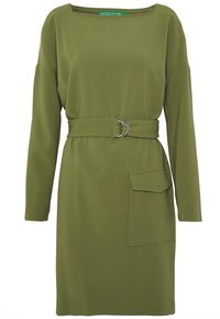 Olivgrön långärmad klänning med bälte som har en cirkulär silverbuckle och en framficka. Mjukt, strukturerat tyg och avslappnad passform.