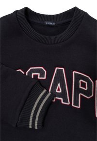 Felpa nera con grandi lettere testurizzate che formano la parola "ESCAPE" in bianco e rosso. Collo e polsini a coste con motivo a righe.