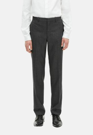 Pantalones de vestir grises de tela suave, de corte ajustado, con frente plano y cinturilla con pasadores para cinturón, combinados con zapatos negros.