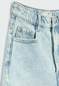 Jeans de denim azul claro con cintura alta, que cuentan con cinco bolsillos y detalles de costura visibles. La tela tiene una textura deslavada.