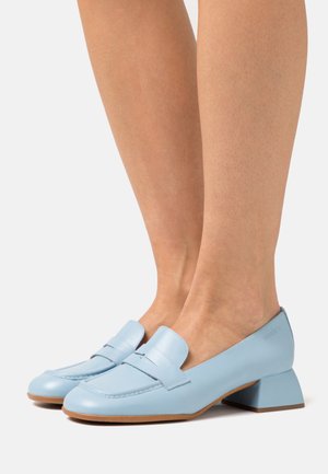 Mocassins en cuir bleu clair avec un petit talon carré et une bande décorative sur le devant. Texture lisse et design de bout arrondi.
