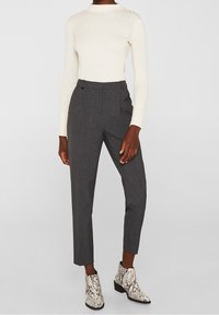 Pantalons gris sur mesure à taille haute, avec des plis et une texture lisse. Assortis avec un top à manches longues à côtes blanches et des bottines en cuir de serpent.