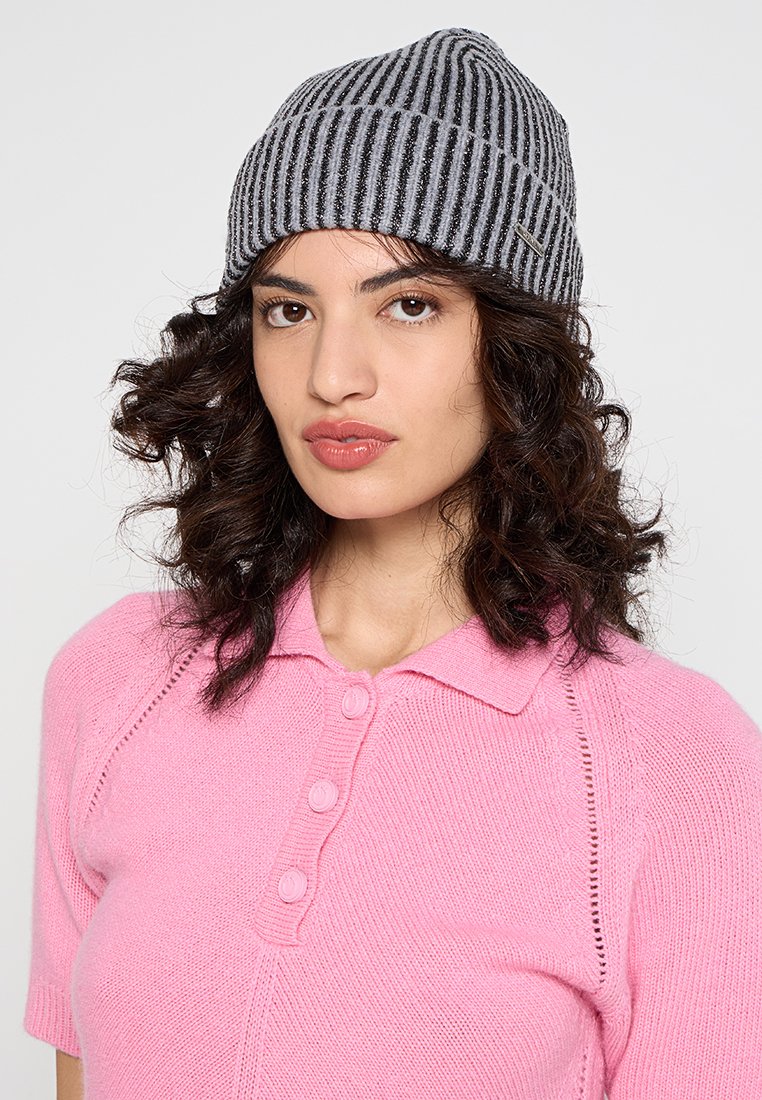 Szary i czarny w paski dzianinowy beanie o miękkiej teksturze i lekko luźnym kroju, w połączeniu z różową koszulą polo z krótkim rękawem i guzikami.