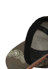 Gorra marrón con interior de malla negra, con un patrón gráfico y detalles naranjas en la visera. Etiqueta interior visible a lo largo del borde.