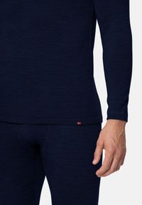 Navyblauw lange mouwen top en bijpassende strakke broek gemaakt van textuurstof, met een klein accent van de Noorse vlag nabij de zoom.