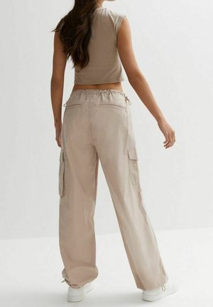 Light beige cargo pants with a relaxed fit, featuring side pockets and elasticated cuffs. Slightly shiny fabric with a smooth texture.