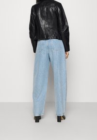 Svart lädercroppad jacka med åtsittande midja; ljusblå högmidjade vida jeans; strukturerad tyg; svarta chunky klackskor.