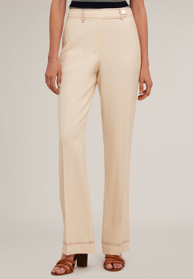 Pantalons larges beige avec une texture lisse, dotés d'une fermeture à bouton et de coutures ton sur ton le long des poches et de l'ourlet.