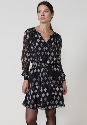 Vestido negro con un patrón de diamantes en gris, que presenta mangas largas, un escote en V, una cinturilla elástica y un tejido ligero y transparente.