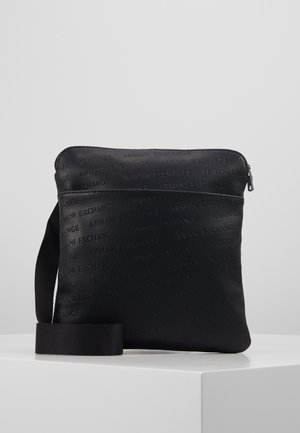 Czarna torba na ramię z tłoczonym wzorem tekstu "Armani Exchange" oraz regulowanym paskiem, umieszczona na białej powierzchni.