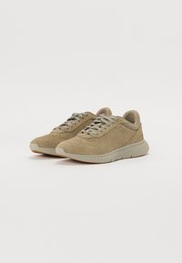 Sneakers beige con una toma in suede e dettagli perforati, lacci piatti, colletto imbottito e suola in gomma texturizzata.