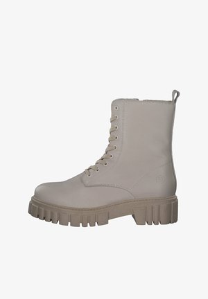 Bottes de combat en cuir beige avec bout rond, six œillets et une semelle en caoutchouc épaisse à nervures. Comprend une languette à l'arrière pour un enfilage facile.