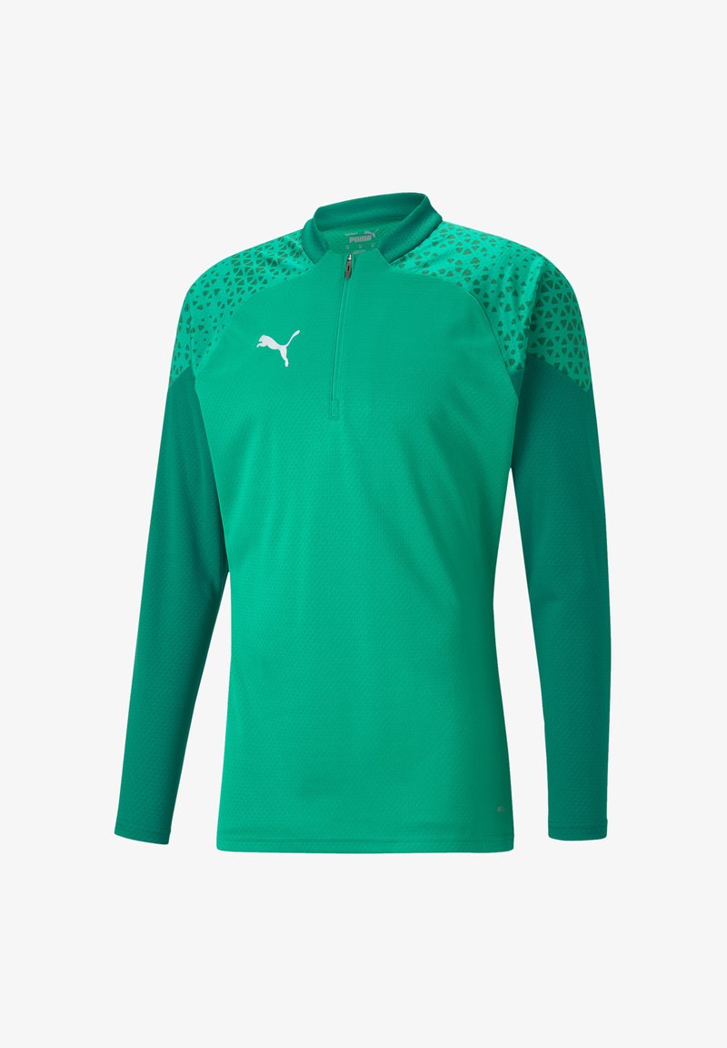 Grünes, langärmliges Sportshirt aus strukturiertem Stoff, mit einem Halb-Reißverschluss-Kragen und kontrastierenden gemusterten Schultern. Weißes Logo auf der Brust.
