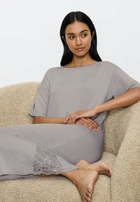 Completo loungewear grigio chiaro composto da una maglietta a maniche corte lunghe e pantaloni aderenti con delicati dettagli in pizzo ai bordi, morbido tessuto.