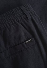 Tengerészkék pamutnadrág elasztikus derékpánttal, lapos elejű kialakítással és GABBA márkajelzéssel a hátsó zsebén. Sima textúra, hétköznapi stílus.