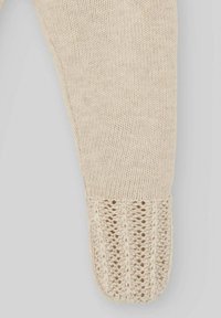 Legging crème tricoté avec un détail de cuff en dentelle texturé au niveau de la cheville. Matériau doux et léger, finition lisse.