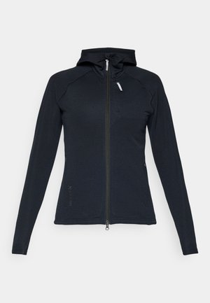 Veste à capuche zippée noire en matériau texturé, avec des manches longues, une coupe ajustée et une petite poche zippée sur la poitrine.