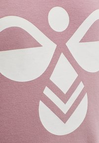 Lyserød tekstil prydet med et stort hvidt grafikdesign, der viser symmet riskelige former og mønstre, herunder afrundede og vinklede former.