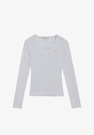 Maglietta bianca a maniche lunghe con scollo a V. Presenta un piccolo logo discreto sul lato sinistro. Tessuto morbido, silhouette aderente.