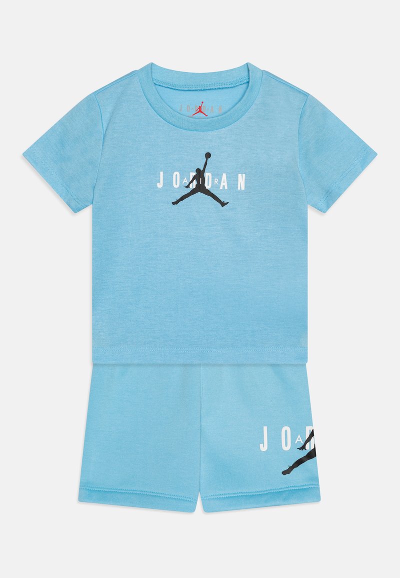 Svetlo modra kratka majica s kratkimi rokavi in kratke hlače, ki vsebujejo črn Jordan logotip in besedilo. Narejeno iz mehkega materiala, z gladko teksturo.