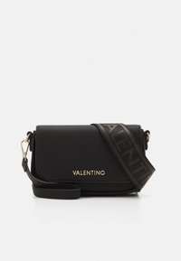 Černá kožená kabelka přes rameno s texturovaným povrchem, zdobená zlatým logem a širokým popruhem s výrazným černým nápisem.