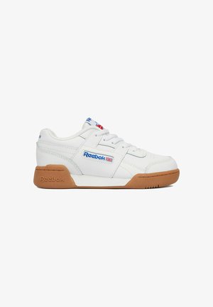Zapatilla baja blanca de Reebok con suela de goma, logo azul y rojo en el lateral, cordones blancos y cuello acolchado, mostrada en perfil lateral.