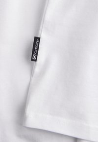 Witte katoenen T-shirt met korte mouwen, uitgerust met een klein zwart "ombre" label op de zijnaad en een gladde, platte zoomafwerking.