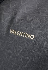 Bolsa de mão de couro preto texturizado com padrão de logo em relevo; apresenta um emblemático detalhe em dourado com o nome "VALENTINO".