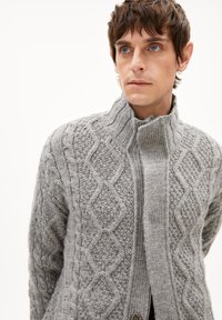 Grauer Strickcardigan mit hohem Kragen und Reißverschluss. Strukturmuster mit Rautenelementen und gerippten Akzenten.