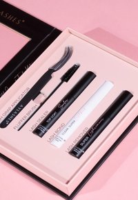 Schwarze und weiße Wimpernprodukte in einer pinken Box: enthält einen Greifapplikator, eine Fluffbürste, Wimpernkleber, Versiegeler, Entferner und Überlack.