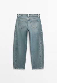 Světle modré džíny z denimu zobrazené z boku se dvěma zadními kapsami a poutky na opasek na bílém pozadí.