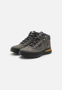 Szare buty trekkingowe z zamszu i gumy, z metalowymi oczkami, teksturowanymi akcentami oraz kontrastującą beżową piętą.