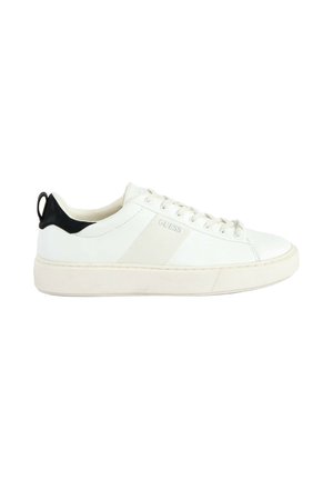 Witte lage sneaker met vetersluiting, zwarte hieltab en vage "GUESS"-bedrukking aan de zijkant, weergegeven op een witte achtergrond.