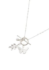 Collier chaîne en argent avec fermoir toggle tenant des breloques : un papillon, une branche avec des feuilles, et une petite perle ronde.