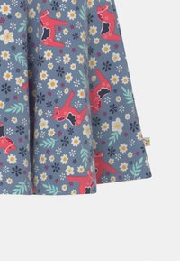 Puuvillamekko, jonka sinisellä taustalla on vaaleanpunaisia eläin- ja kukkakuvioita. Kuvioissa on vihreitä lehtiä sekä valkoisia, keltaisia ja mustia kukkia.