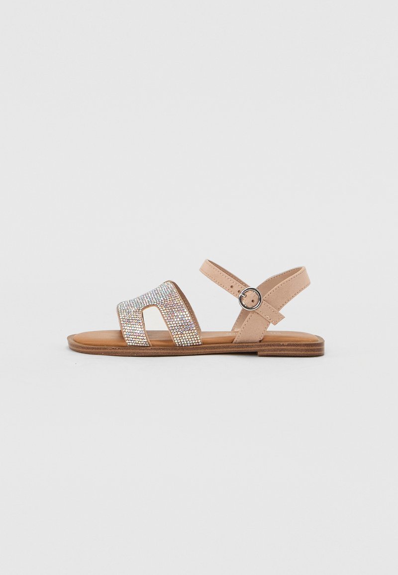 Sandales en cuir beige avec trois larges brides ornées de strass transparents, une bride à la cheville à boucle et une semelle plate en bois.
