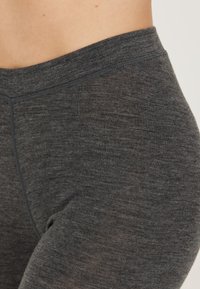 Dunkelgraue Leggings aus weichem, strukturiertem Stoff mit einem glatten Bund. Nähte sind an den Seiten sichtbar.