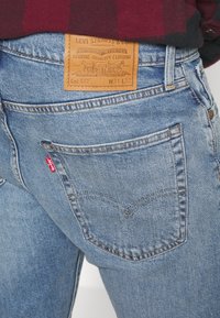 Ljust blå denimjeans med en lädermärkning märkta "Levi Strauss & Co." och röd etikett. Har klassisk sömnad på bakfickan.